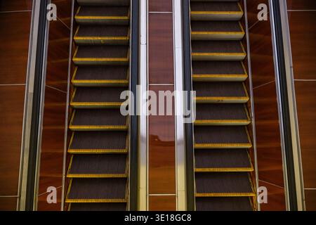 Escalators moving up and down in modern building interior, creating parallel lines Stock Photo
