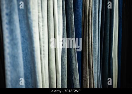 Blue denim jeans hanging in a row, showing different shades and textures Stock Photo