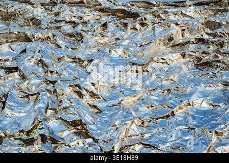 Wrinkled aluminum foil background showing abstract patterns and shiny reflections Stock Photo