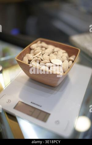 Almonds in a wooden bowl on a kitchen scale with weight indicator, weigh Stock Photo