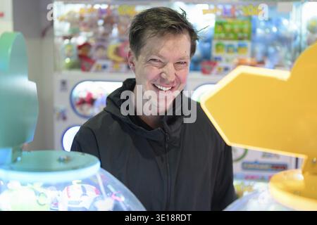 Happy man playing arcade video games indoors looking excited Stock Photo