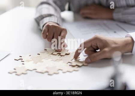 Businessman hands putting together puzzle pieces with Team Building join together and Business Collaboration Concept in office Stock Photo