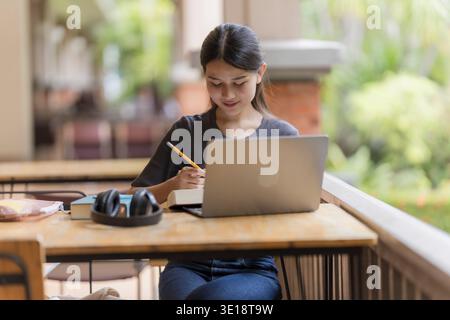 Young Asian Female Student Reading Books in Library Stock Photo