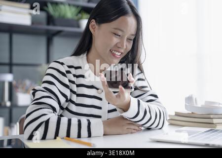 Asian Woman Engaging with Voice Assistant on Smartphone in Modern Home Stock Photo