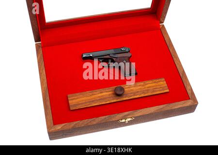 Open wooden display case featuring a miniature pistol model on a vibrant red velvet background. Stock Photo