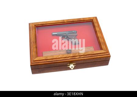 Miniature pistol model inside a wooden display case with red velvet lining on white background. Stock Photo