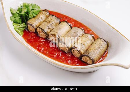 Savory rolls made from tender roasted eggplant are filled with a flavorful mixture and served on a vibrant tomato sauce. A fresh garnish of herbs comp Stock Photo