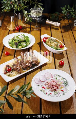 A beautifully arranged table showcases delicious dishes like salad, seasoned meat, and seafood, garnished with fresh herbs and vibrant cherry tomatoes Stock Photo