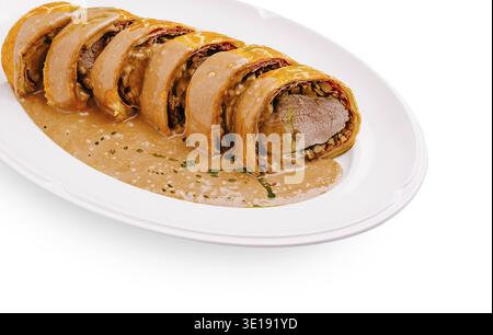 Tender roast beef is elegantly sliced and arranged on a white plate, accompanied by a creamy sauce. Accent flavors enhance this gourmet dish suitable Stock Photo