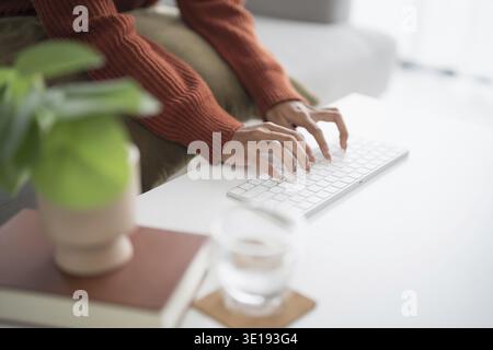 Beautiful asian Woman working by using wireless bluetooth white keyboard computer Hands typing on keyboard. Technology business Concept Stock Photo