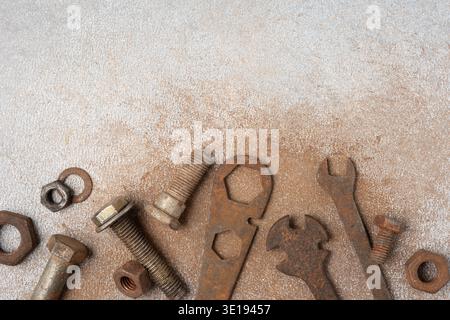 Old rusty wrenches, bolts and nuts arranged on grey textured background. Industrial repair and maintenance concept with vintage metal tools, workshop Stock Photo