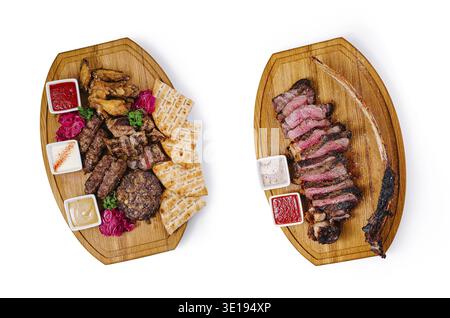 Two oval wooden boards presenting grilled meat assortment with sauces and pita bread, isolated on white background Stock Photo