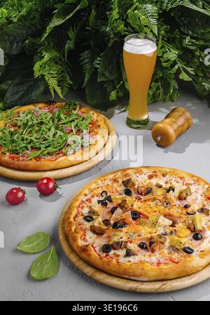 Two different pizzas served on wooden boards with a glass of beer, perfect for sharing with friends at a restaurant or at home Stock Photo