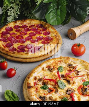 Two tasty pizzas with pepperoni and vegetables, fresh ingredients on a gray surface Stock Photo