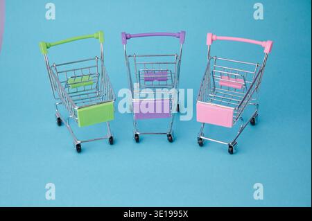 Three small shopping carts sit on a blue background. Stock Photo