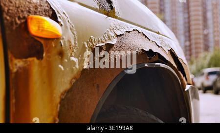 Rusty fender with peeling paint on damaged car parked on city street Stock Photo