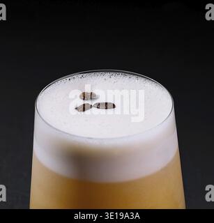 Sophisticated whiskey sour cocktail with frothy foam. Served in a glass on a dark background. A trendy and elegant classic drink for nightlife and hap Stock Photo