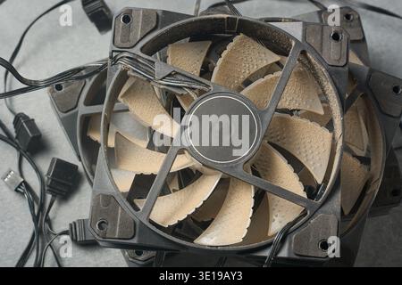 stack of dusty black computer cooling fans on textured gray surface, old technology with wires and cables, close-up in top view, e-waste Stock Photo
