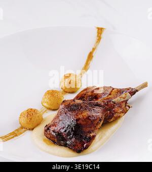 Roasted chicken legs are served on white plate with mashed potatoes and crispy balls Stock Photo