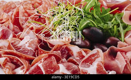 Selection of thinly sliced cured meats and fresh garnishes close up Stock Photo