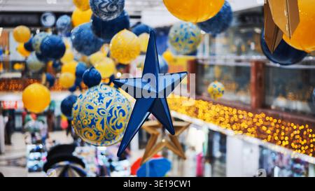 Blue christmas star hanging in a shopping mall with yellow and blue decorations Stock Photo