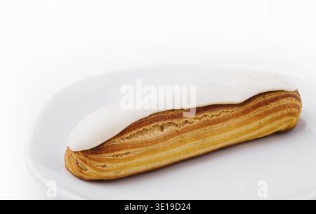 Freshly baked eclair with creamy filling on a clean white plate isolated on white background Stock Photo