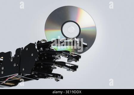 Real robotic hand with compact disc. Concepts of AI development and data storage Stock Photo