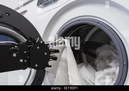 Closeup of real robot's hand and washing machine. Concept of Artificial intelligence development and robotic process automation Stock Photo