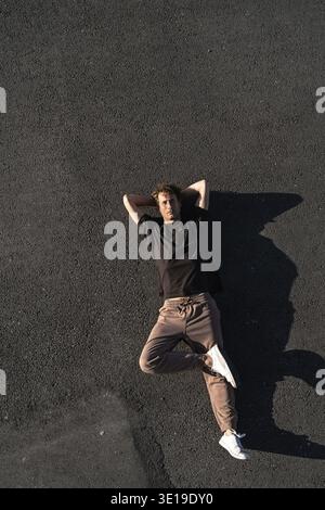 Top view of young adult man carefree lying on the asphalt Stock Photo