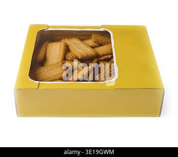Delicious rectangular shortbread cookies with sesame seeds are packed in a yellow cardboard box with a transparent window on a white background Stock Photo