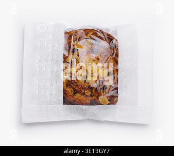 Top view of a delicious almond croissant in a translucent paper bag, isolated on a white background Stock Photo