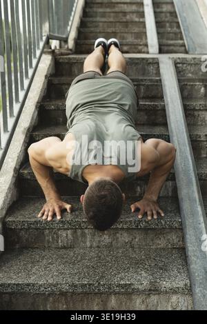 Young and muscular man is doing push-ups during calisthenic workout on a street Stock Photo