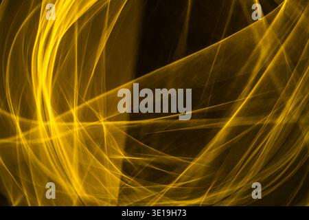 Golden energy streams and glowing light trails flow across a dark background, forming dynamic, fluid patterns and vibrant, futuristic textures suggest Stock Photo