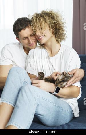 Young beautiful couple with their lovely cat relaxing at home Stock Photo