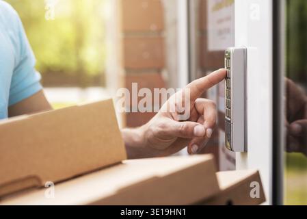 Closeup of delivery man hands with a packages is pressing buttons on a doorbell Stock Photo