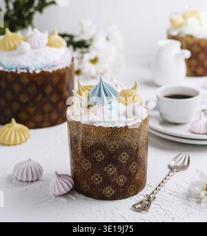 Festive russian kulich cake adorned with colorful meringue, on a table set for easter Stock Photo