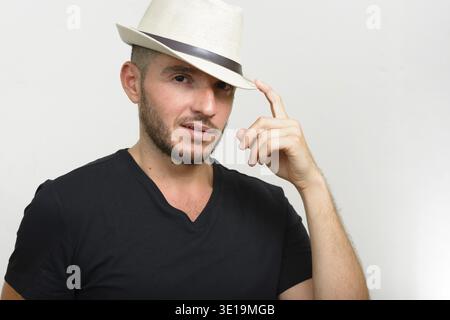 Studio shot of handsome bearded Hispanic man wearing hat against white background Stock Photo
