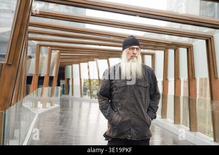 Portrait of mature handsome bearded hipster man at footbridge in the city Stock Photo
