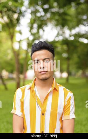 Portrait of young handsome multi ethnic man relaxing at the park outdoors Stock Photo