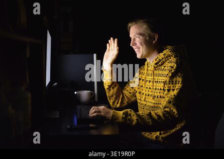 Portrait of young handsome man working overtime at home late at night in the dark Stock Photo
