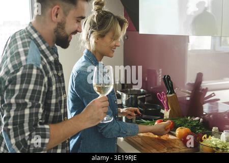 Young and happy couple cooking launch and drinking wine together in the kitchen Stock Photo