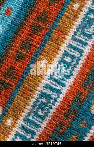 Macro close-up of colorful traditional woven textile showing geometric striped pattern and detailed threads in turquoise, orange, white and brown. Stock Photo