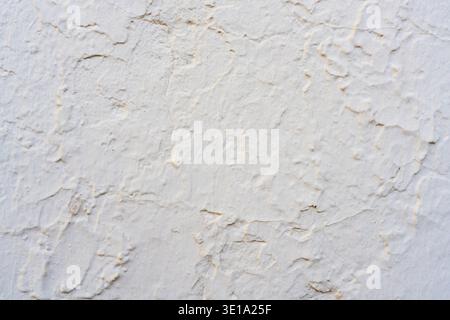Weathered white plaster wall surface showing uneven texture and fine cracks. Stock Photo