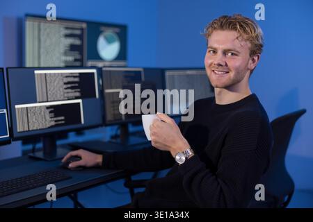 Young IT professional monitors system logs in SOC control room Stock Photo