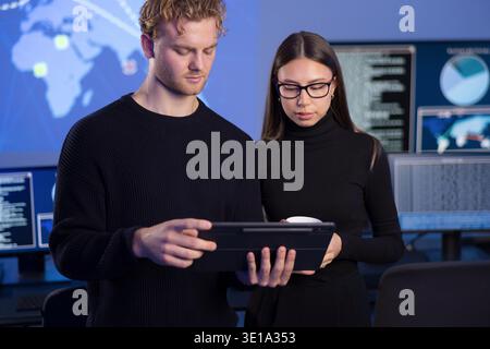 Two cybersecurity professionals analyzing data in a secure operations center Stock Photo