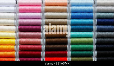 Colorful sewing threads arranged in rows, vibrant textile background with many thread spools in rainbow colors, craft and tailoring concept Stock Photo