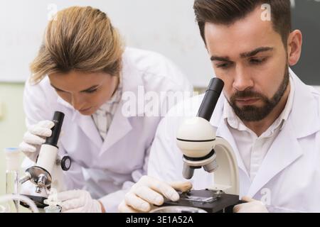 Two scientist colleagues are using microscopes during research work in a laboratory Stock Photo