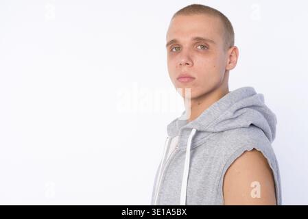 Studio shot of young bald rebellious man wearing hooded shirt isolated against white background Stock Photo