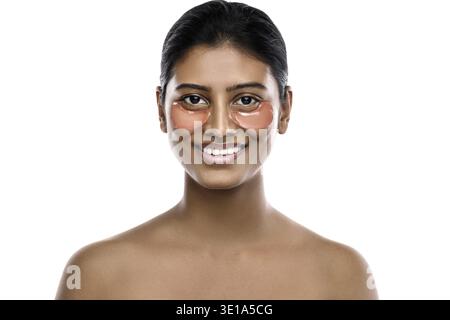 Beautiful Indian woman with hydrating eye patches under her eyes on white background Stock Photo