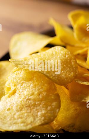 Crispy golden potato chips close up, piled in warm light, visible salt crystals and ruffled edges, highdetail macro Stock Photo